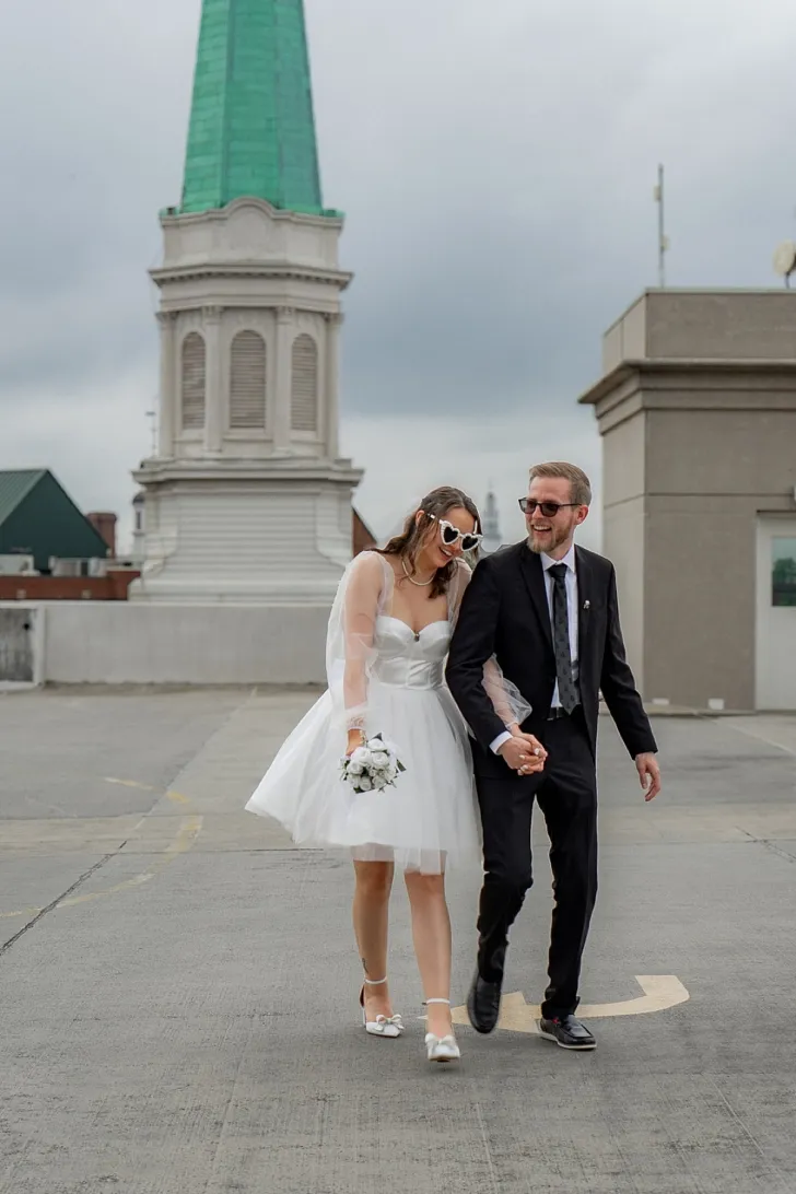 bride and groom holding hands outside of city hall