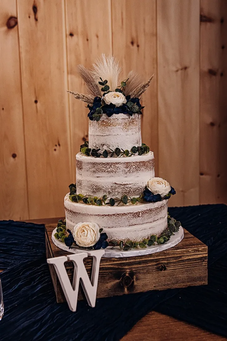 three tiered white wedding cake with white roses and a large letter W