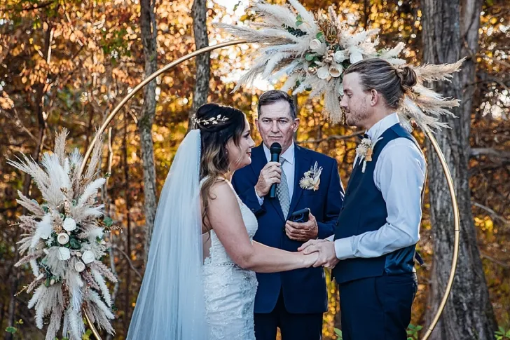 bride and groom holding hands while officiant speaks during wedding ceremony