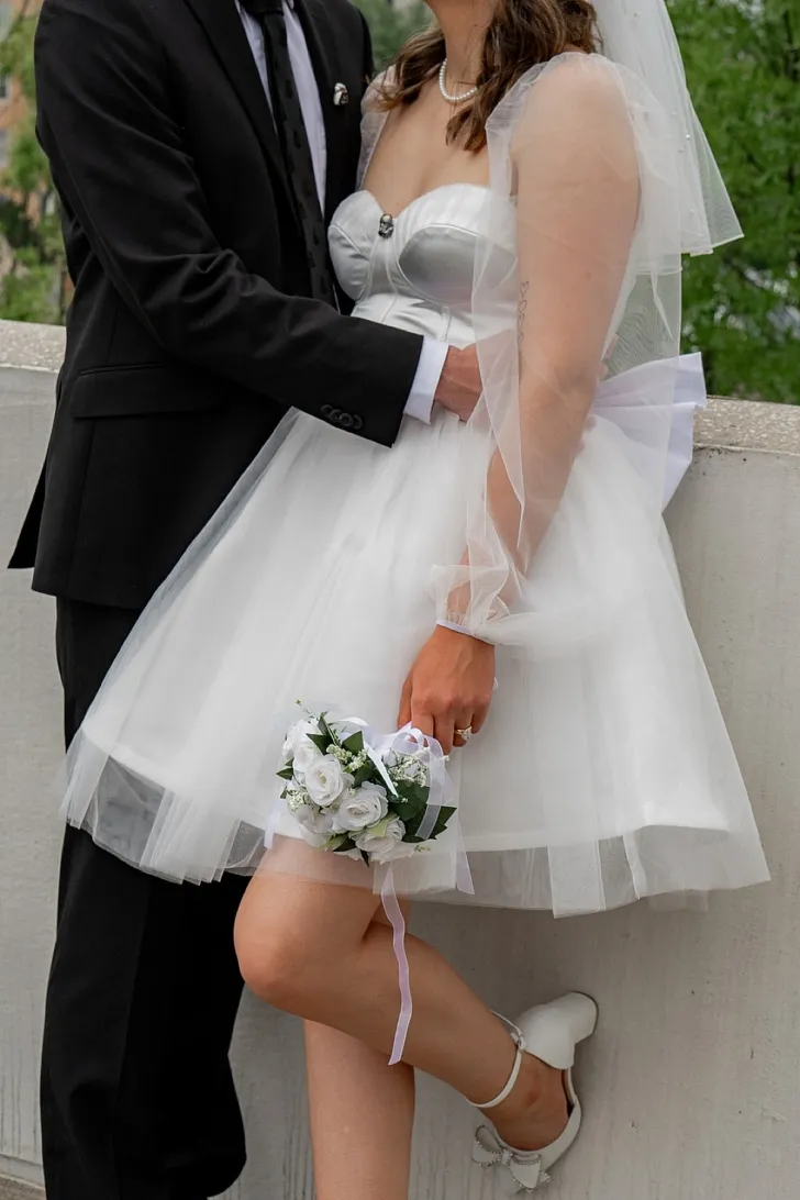 bride holding bouquet and being embraced by groom