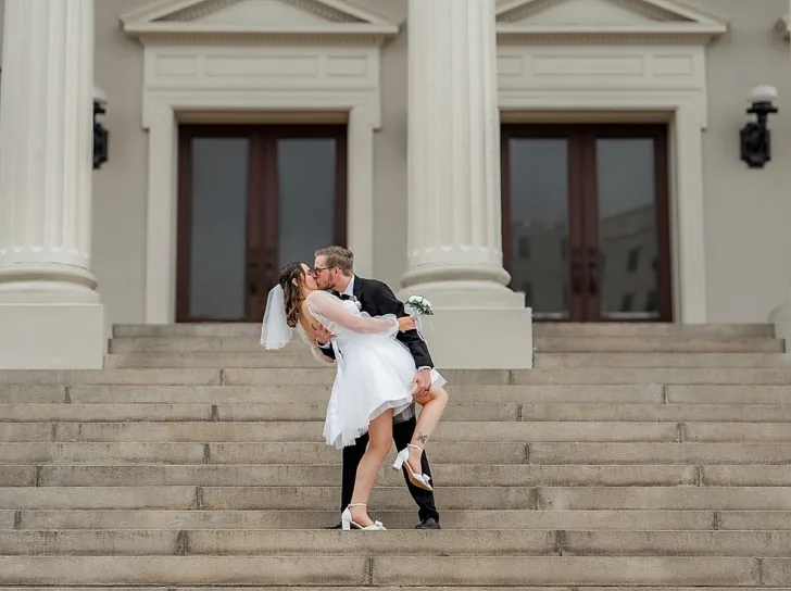 groom dipping bride and kissing her on the steps of city hall
