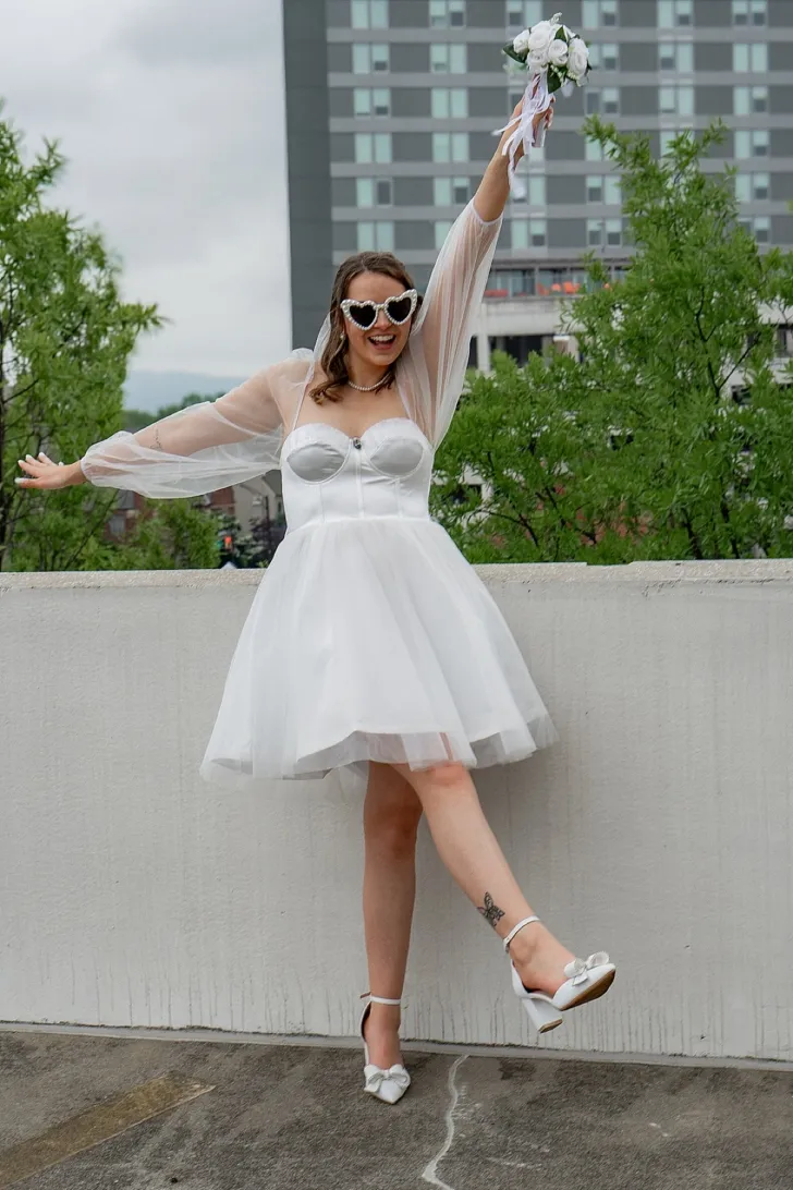 bride posing in short wedding dress and holding bridal bouquet