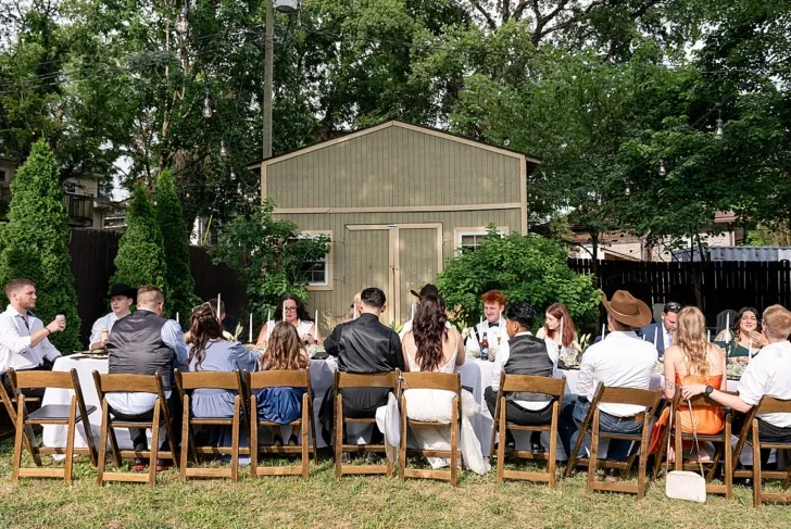 brid mand groom sitting with wedding guests at outdoor reception